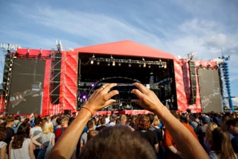 1750757381_man-holding-smartphones-hands-photographing-summer-outdoor-music-concert-festival-1.jpg